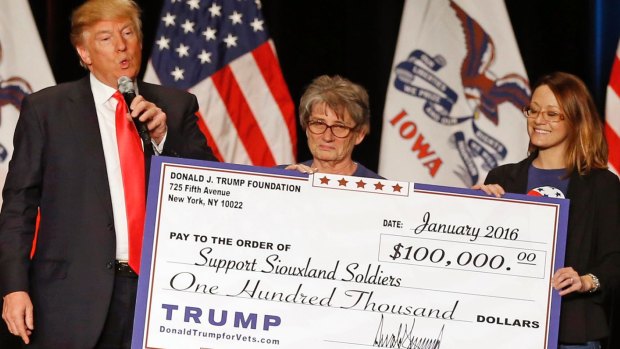 Donald Trump hands a giant cheque to Support Siouxland Soldiers during a campaign event in Iowa in 2016, one of several illegal payments made using charity funds. 
