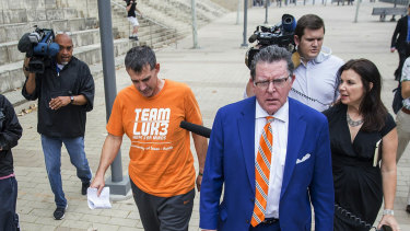 Michael Center, the men's tennis coach at the University of Texas, is seen in an orange T-shirt leaving court in Austin, Texas, after being charged in connection with the admissions scam.