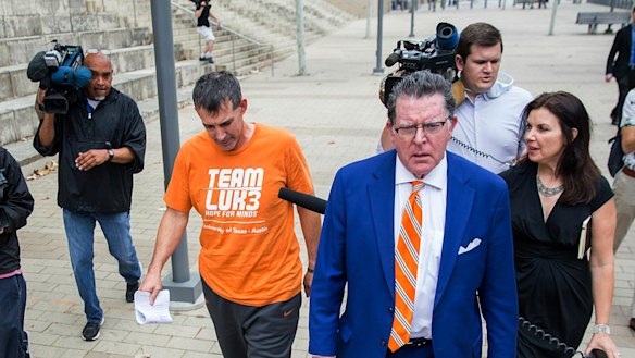 Michael Center, the men's tennis coach at the University of Texas, is seen in an orange T-shirt leaving court in Austin, Texas, after being charged in connection with the admissions scam.