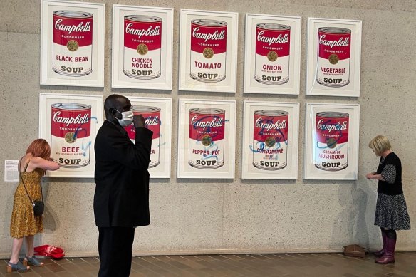 Protesters glue themselves to Warhol Campbell’s Soup display at the National Gallery of Australia.