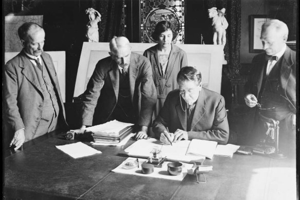 Kathleen Butler watches with John Bradfield (first left) as the minister signs the contract to build the Harbour Bridge, March 24, 1924. 