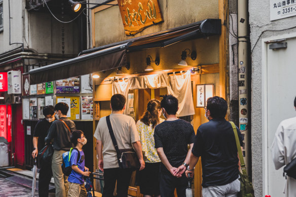 Ramen heads queue for a bowl outside of a popular ramen restaurant in Tokyo.