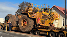 The giant trucks squeeze past houses, businesses and schools.