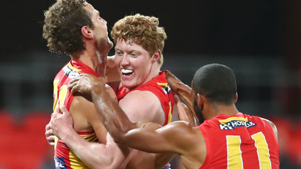 Matt Rowell (middle) is mobbed by teammates while playing for the Gold Coast Suns. 