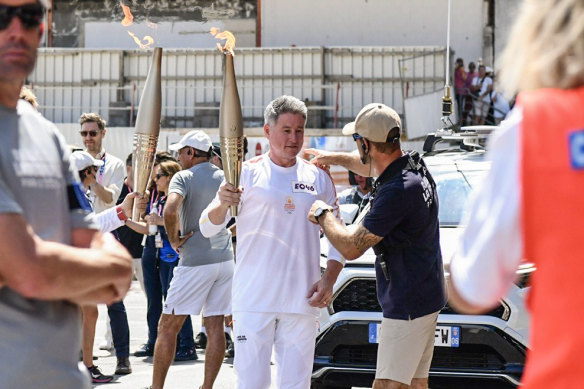 Then-Nine CEO Mike Sneesby carries the Olympic torch in Paris while staff at home were engaged in industrial action.