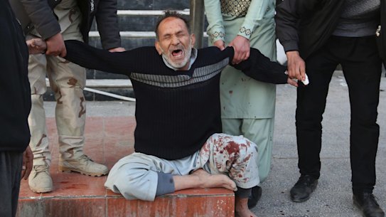 A relative of a victim is helped as he cries after a deadly suicide attack in Kabul on January 27, 2018. 