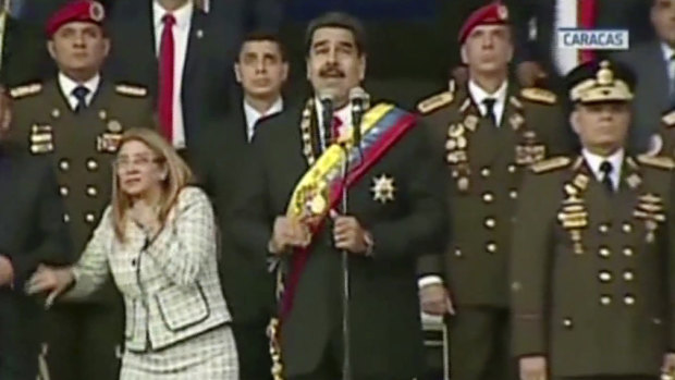 In this still from a video provided by Venezolana de Television, President Nicolas Maduro, centre, delivers his speech as his wife Cilia Flores looks up after being startled by an explosion in Caracas on Saturday.