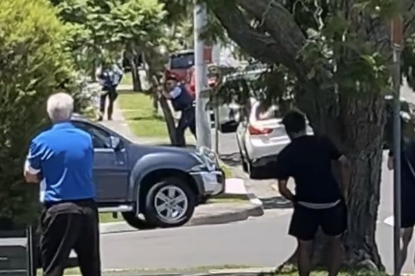 A police officer points his gun towards a medical centre in Nowra. 