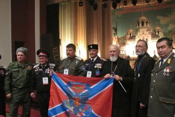Boikov with priests and officials in Russia in 2015 holding the flag of Novorussia, an unrecognised area of southern Ukraine that Russia claims.