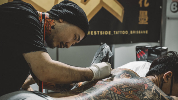 A professional tattoo artist taking the time to perfect a tattoo on a client at the Australian Tattoo Expo, unlike the terrible tattooes displayed at the competition.