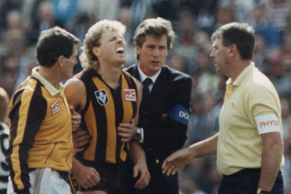 Dermott Brereton receives attention  after being flattened by Geelong's Mark Yeates in the 1989 grand final.