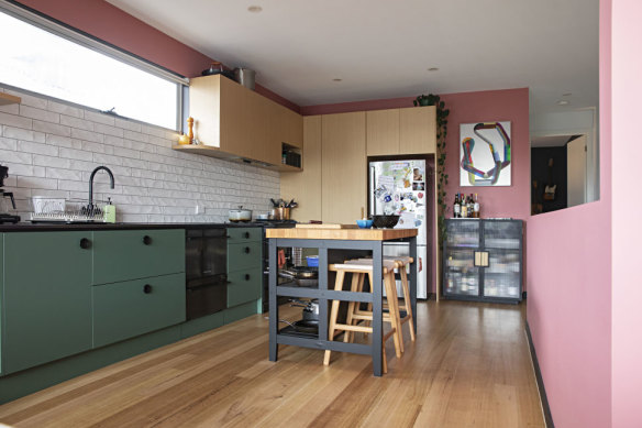 The couple injected their personalities into the home, adding green cabinetry, pink walls, textured tiles and three ovens to the kitchen.