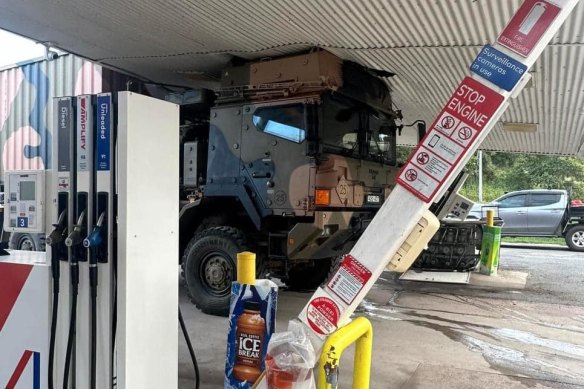 The truck wedged under the awning of the petrol station.