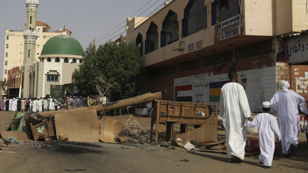 Sudanese men and a child headed to a mosque navigate a roadblock set by protesters on a main street in the Sudanese capital Khartoum to stop military vehicles from driving through the area on Wednesday.