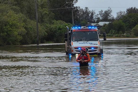 An SES worker wades through waist-deep floodwaters.