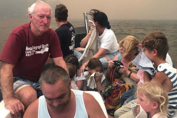 Michael Cripps, left, and son Brett Cripps, in white singlet, crammed 12 people and a dog into a small boat and saved their lives as fires raged at Lake Conjola on New Year's Eve.