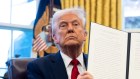 US President Donald Trump displays a signed automotive tariff executive order in the Oval Office.
