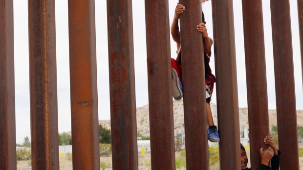 Children from Anapra, Mexico, climb a section of the new border wall recently built in New Mexico. 