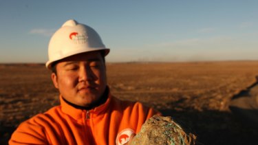 A worker holds a turquoise rock taken from the Oyu Tolgoi mine. 