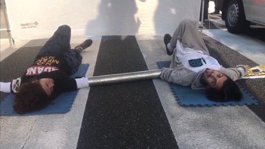 Two animal rights protestors are seen after having glued themselves to a road in Brisbane's CBD, on Tuesday, June 18, 2019.  The pair caused traffic delays for three hours in Brisbane on Tuesday when they superglued themselves to a zebra crossing in the CBD. 