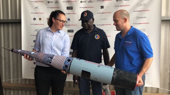 From left to right: Carley Scott, chief executive of ELA, Djawa Yunupingu, traditional owner, from Gumatj Corporation, Blake Nikolic, chief executive of ELA customer Black Sky Aerospace. Painting on the cone of the rocket by painting by artist Dorothy Djakangu Yunupingu. 