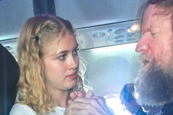 Clara Daly, 15, using American Sign Language to sign letters into the hands of passenger Tim Cook, who is blind and deaf, on an Alaska Airlines flight.