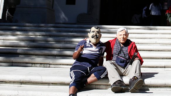 Enedino Camarillo, wearing a mask representing former Mexican President Vicente Fox, and Luis Duque wearing a mask depicting Andres Manuel Lopez Obrador, sit on the front steps of the Casa Miguel Aleman, the presidential residence know as Los Pinos, in Mexico City, on Saturday.