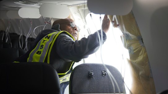 A National Transportation Safety Board  investigator examining the fuselage plug area of Alaska Airlines Flight 1282.