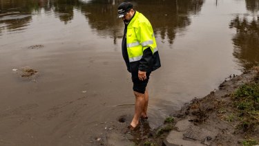 Resident Steve Arnold walks in floodwaters at Moorebank, in Sydney’s west, on Monday.