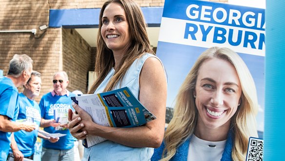 Much in common but only one victor: the teal Jacqui Scruby on polling day, flanked by the poster of her Liberal rival, Georgia Ryburn.