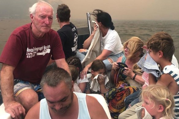 Michael Cripps, left, and son Brett Cripps, in white singlet crammed 12 people and a dog into a small boat and saved their lives as fires raged at Lake Conjola on New Year's Eve.