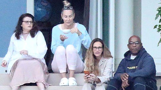 Julia Roberts - second from right - takes in the view from Coolong’s back porch in Vaucluse, much to the delight of the paparazzi on the harbour.