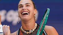 The athlete brought a pop of colour to the court, with a bright orange matching set peeking through the semi-sheer material of her dress.
