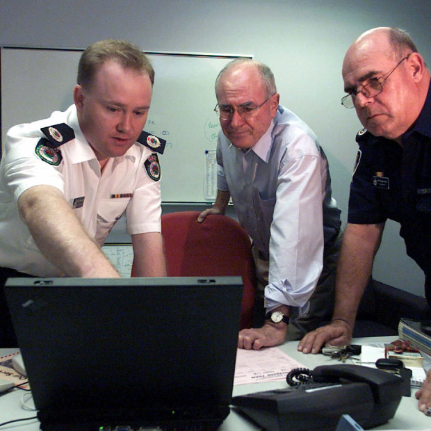 Then prime minister John Howard is briefed by Shane Fitzsimmons and Phil Koperberg of the RFS before visiting the bushfire devastated suburb of Warragamba in 2001.