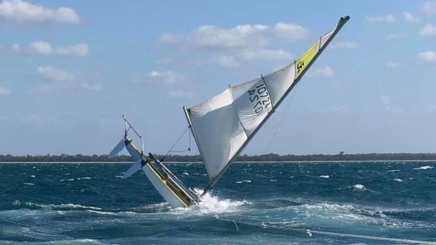 A woman spent at least two hours clinging to her overturned 14-foot catamaran off Hervey Bay on Sunday.