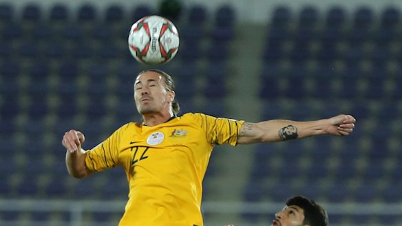 Flying solo: Australia's Jackson Irvine wins a header against Uzbekistan in front of a bank of empty seats  at Khalifa bin Zayed Stadium in Al Ain.