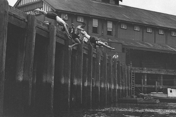 Young people dive from a wharf into Sydney Harbour at Millers Point in the 1930s.