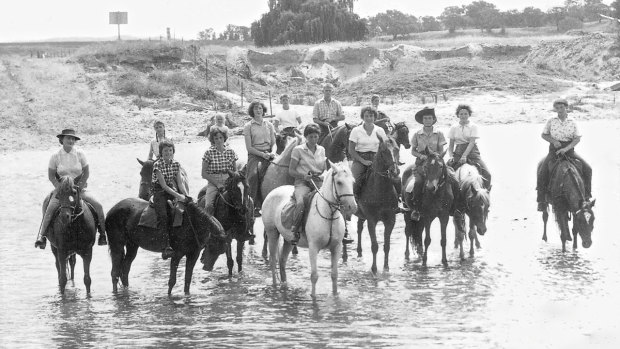 Bobby Llewellyn (far left) with participants at her horse riding school, including her daughter Jan (far right) crossing the Molonglo river near Acton, circa 1958.