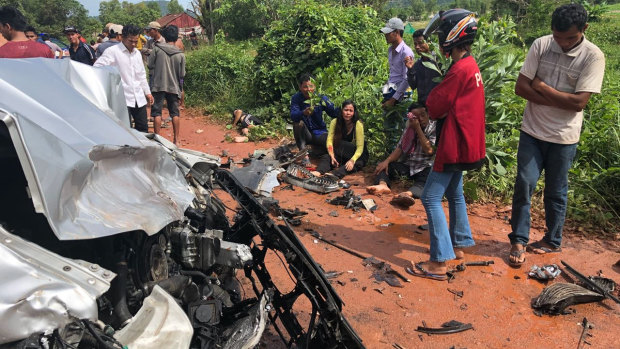 Onlookers stand around the mangled wreckage of Cambodia's Prince Norodom Ranariddh's car.