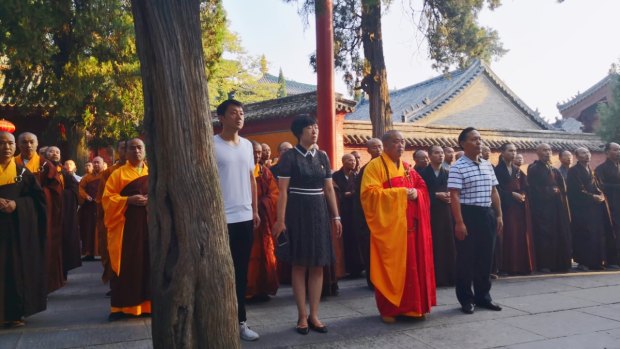 People believed to be officials attend the flag-raising ceremony, the first for the Shaolin Temple.