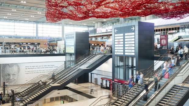 From the ceiling of Terminal 1 hangs a massive metal “net” of red, a sculpture known as The Magic Carpet.