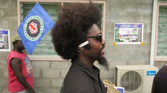 A man plants a Bougainville flag in his hair as he queues up to vote on the opening day of the territory's independence referendum.