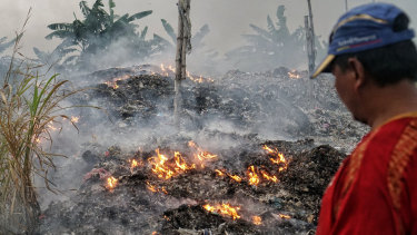 A man watches over the burning of paper company waste because he can't sell it to tofu or cracker factories.