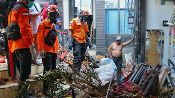 Udin, shirtless, and an East Java evacuation team looks at a spot where they suspected a body is burried. 