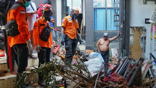 Udin, shirtless, and an East Java evacuation team looks at a spot where they suspected a body is burried. 