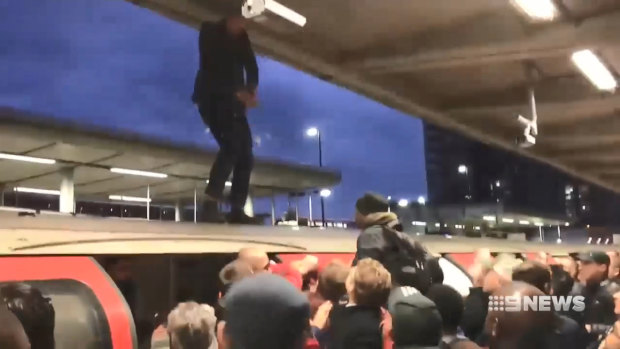 Footage shows angry commuters clashing with a protester who had climbed onto the roof of a train.