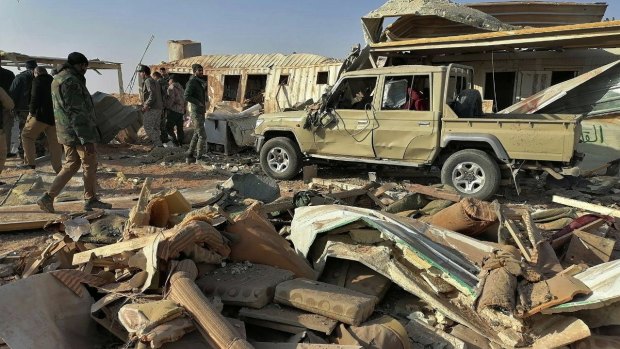 Fighters from the Kataeb Hezbollah, or Hezbollah Brigades militia, inspect the destruction at their headquarters in the aftermath of a US airstrike in Qaim, Iraq, on Monday.