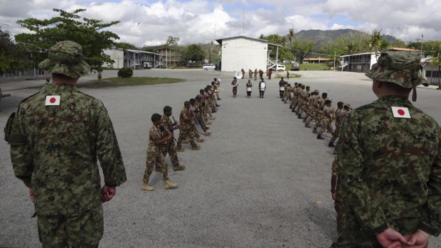 Japanese soldiers watch a march-past by Papua New Guinea's military band.