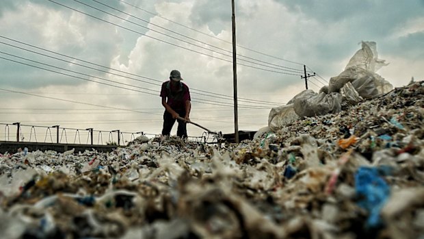 A man in Bangun village in East Java spreads out wet paper company's waste to dry it for use for burning in tofu manufacturing.