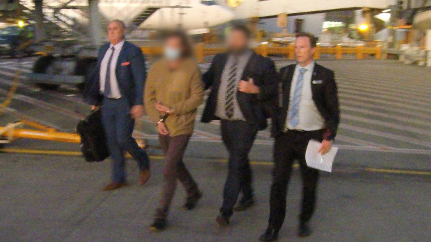 Toby Moran, 42, is escorted across the tarmac as he is extradited from Western Australia to face a homicide charge in NSW.